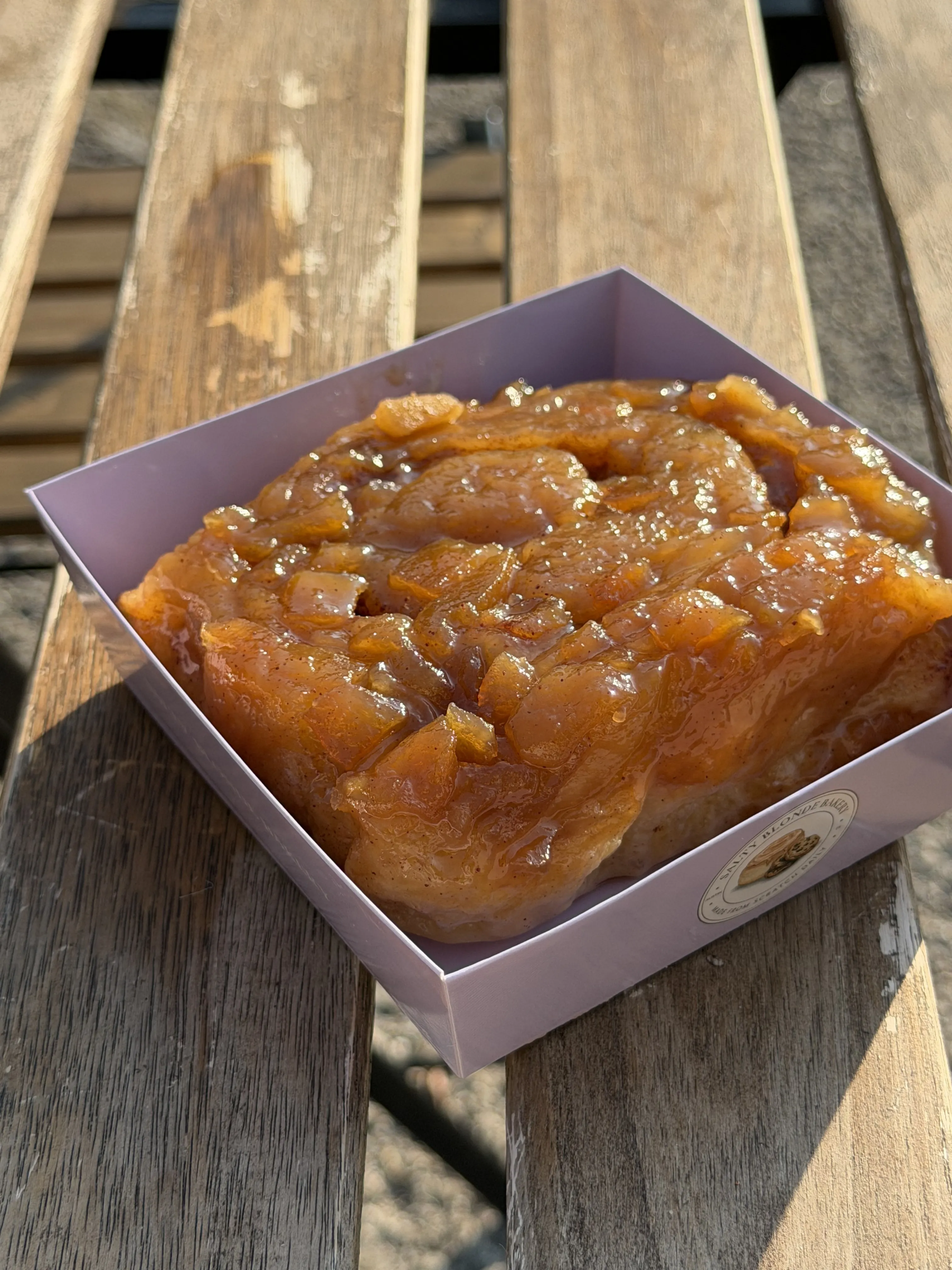 Glossy amber-colored specialty roll in a lavender Salty Blonde box outdoors.