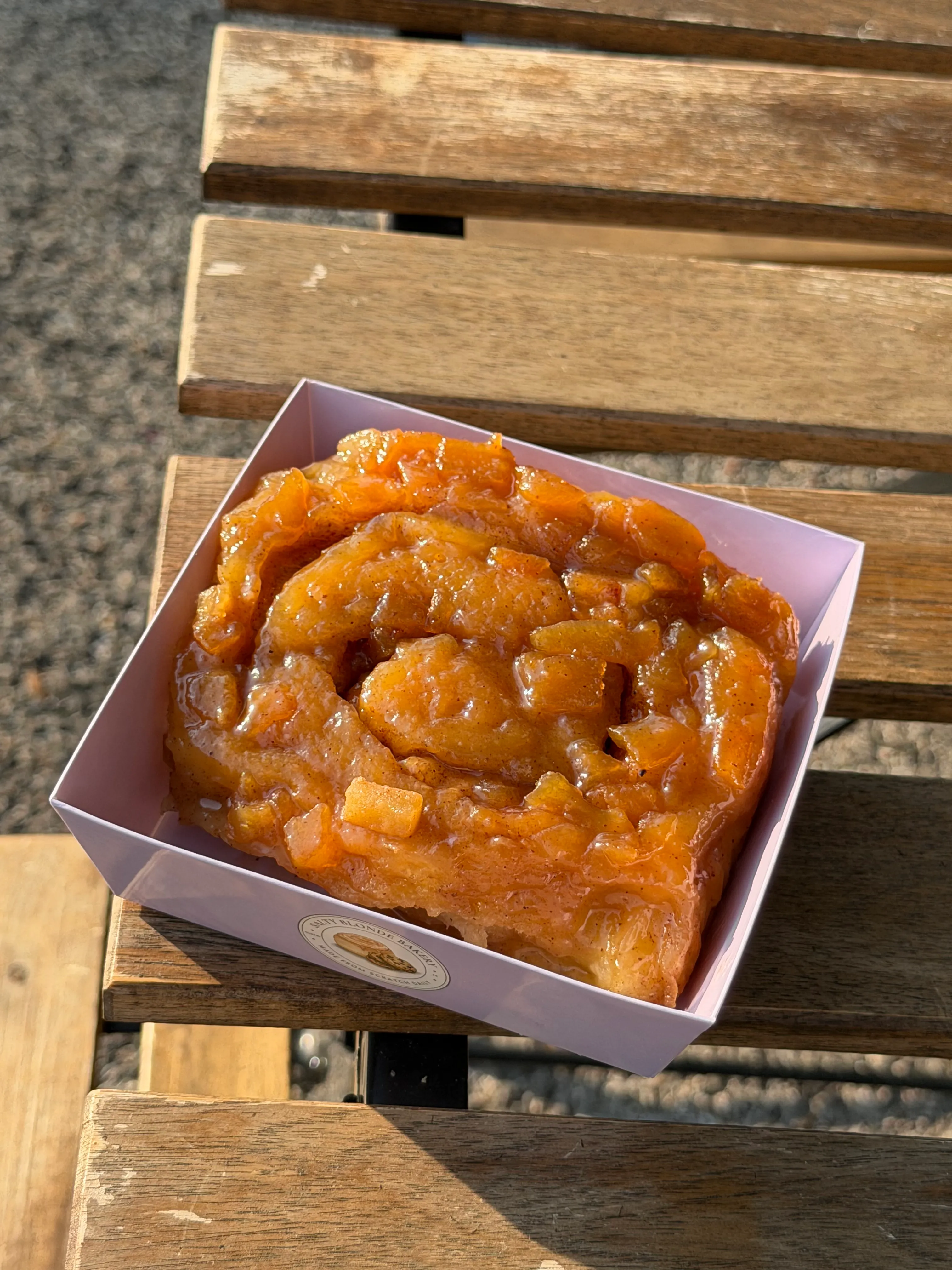 Glossy fruit-topped specialty roll in a lavender bakery box.