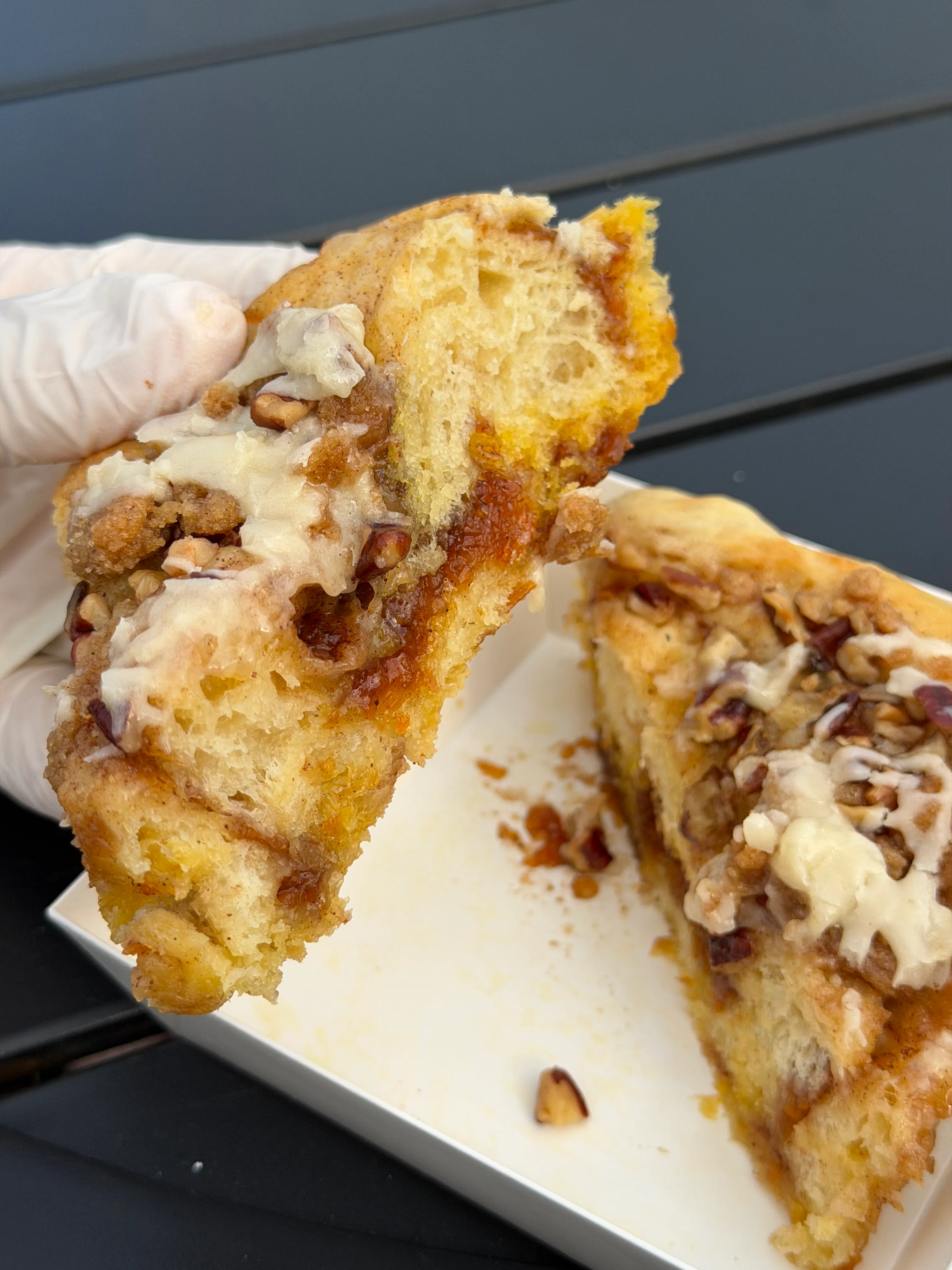 Close view of a torn bakery roll showing a gooey spiced filling and crumb topping.