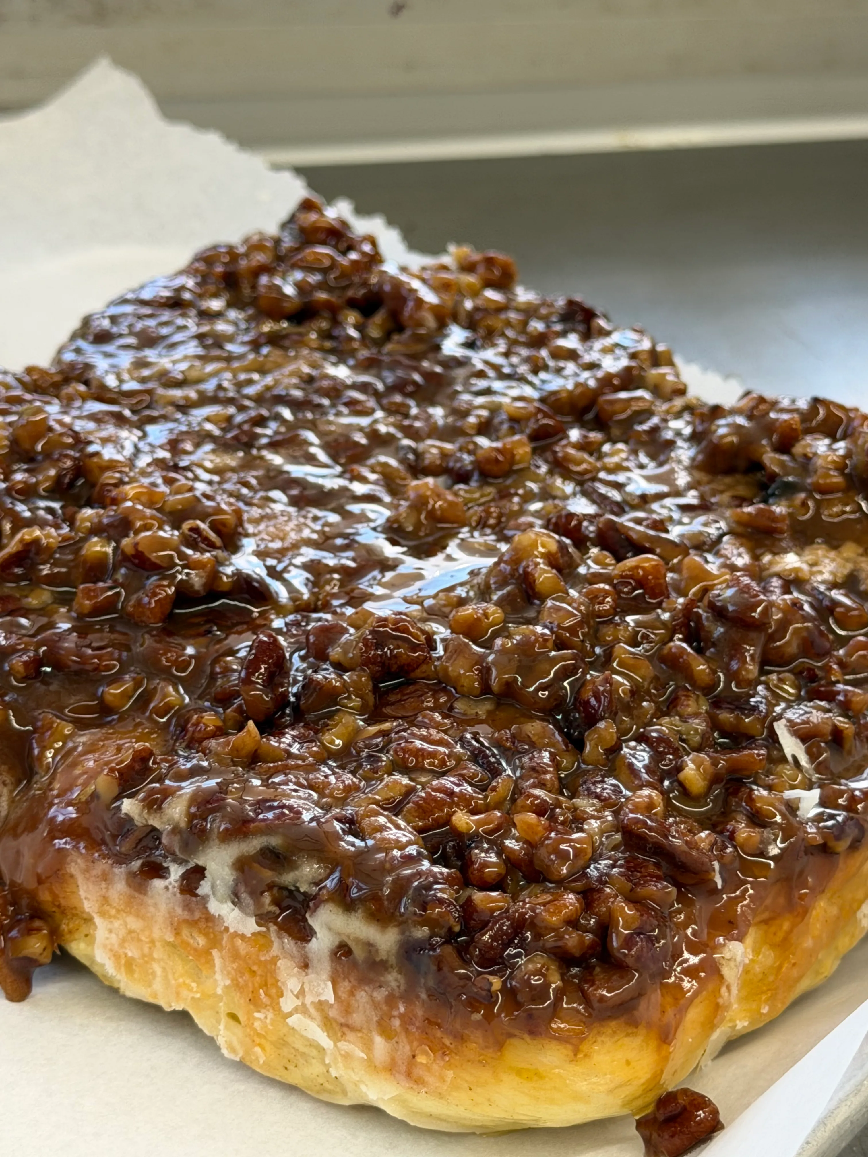 Glossy pecan-topped sticky bake shown close enough to see the caramelized surface.